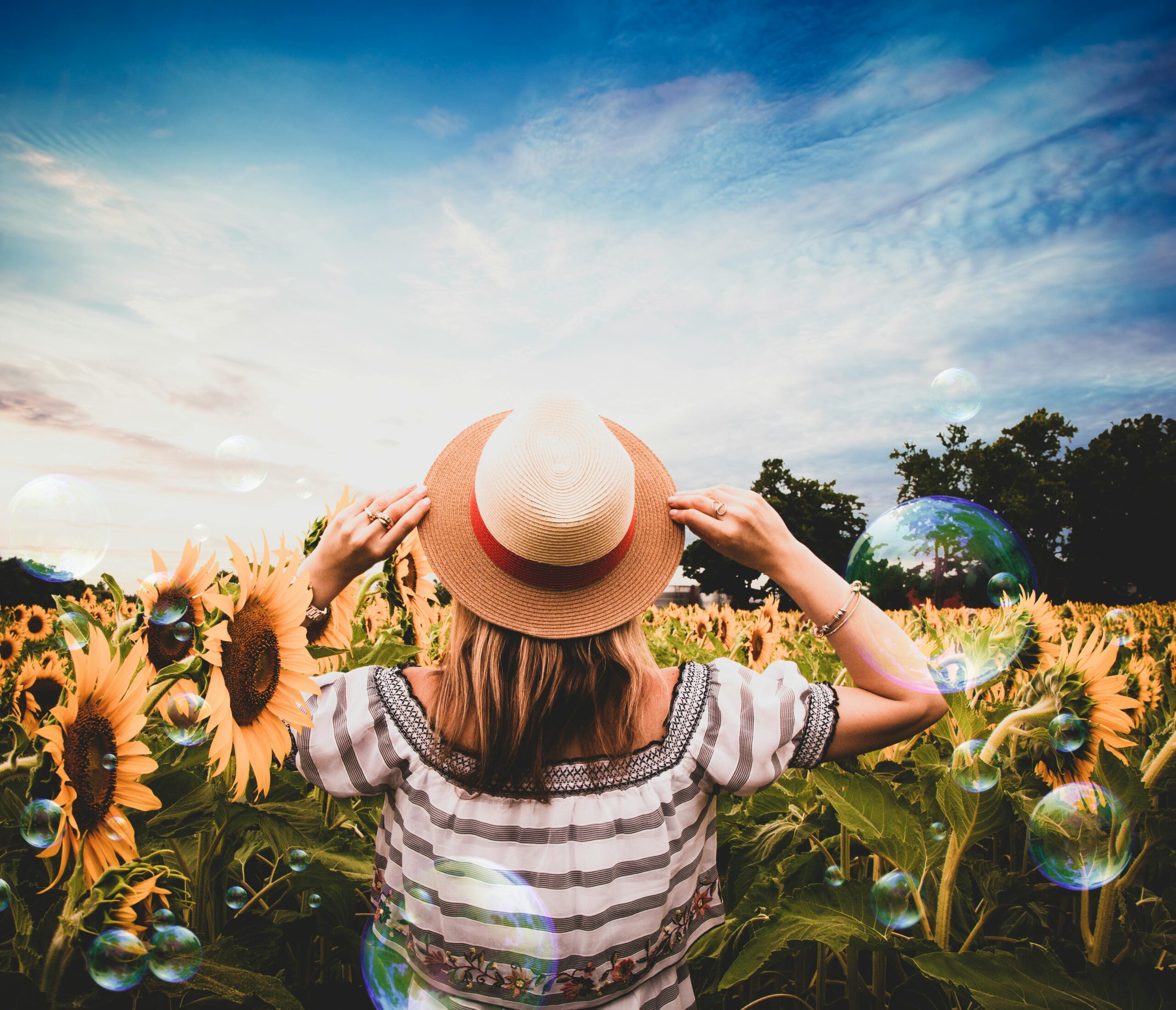 Femme se tenant dans un champ de tournesols profitant de l'air frais de l'été