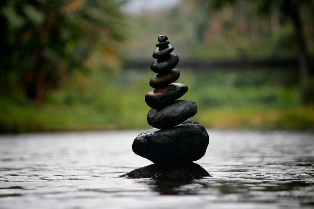 Galets en équilibre sur une rivière évoquant paix intérieure, tranquilité, sérénité et bien-être.